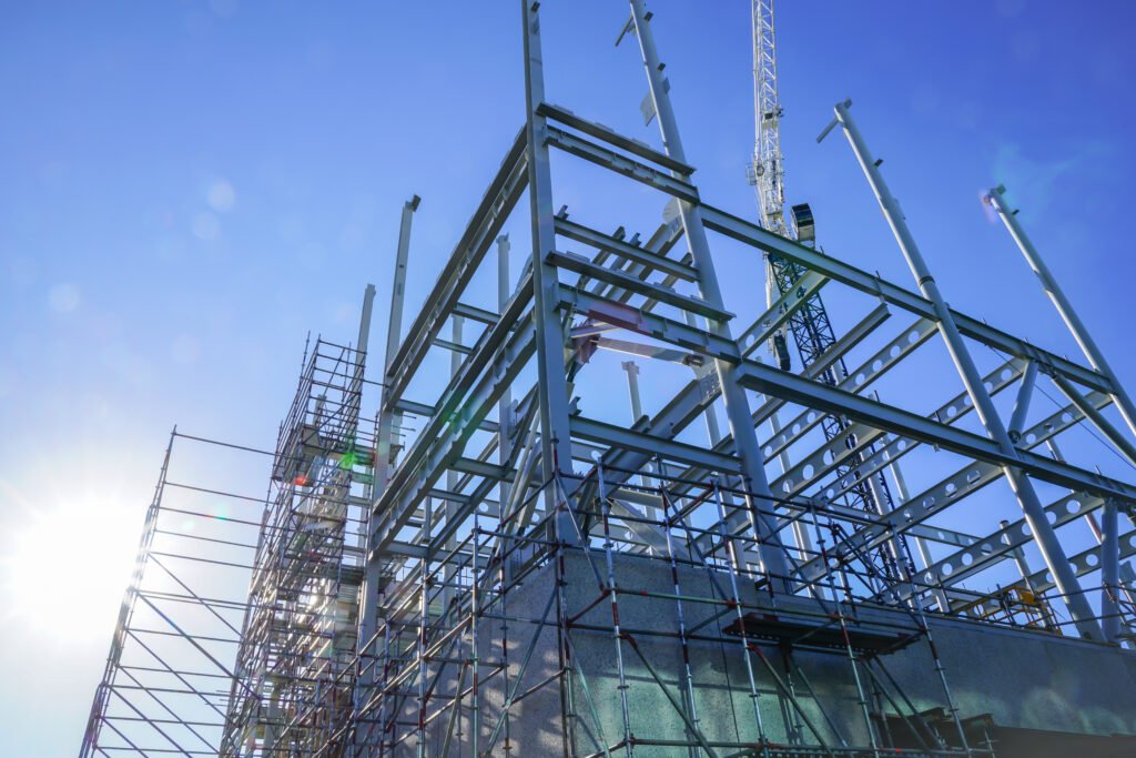 White structural steel framework for new building against deep blue sky.